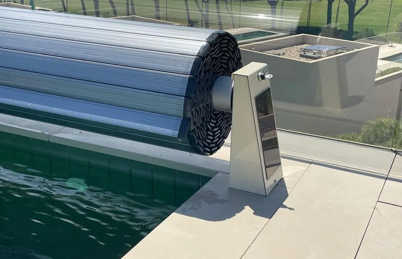 Enrolador de cobertura automática no bordo da piscina, com caixa de comando ao lado